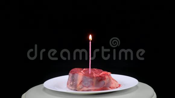 一块牛肉中间有一根点燃的蜡烛背景是黑色的视频的预览图