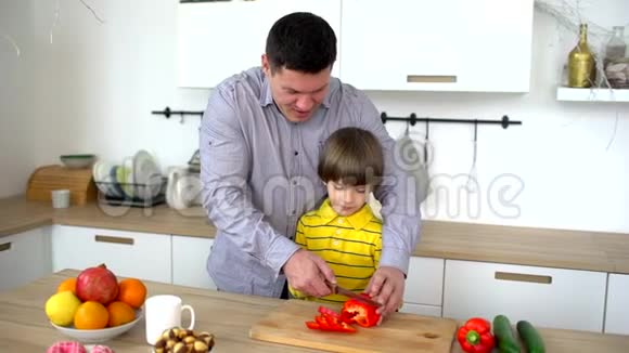 父亲和儿子在家厨房里切蔬菜父亲协助非常可爱的儿子在厨房切蔬菜切割视频的预览图
