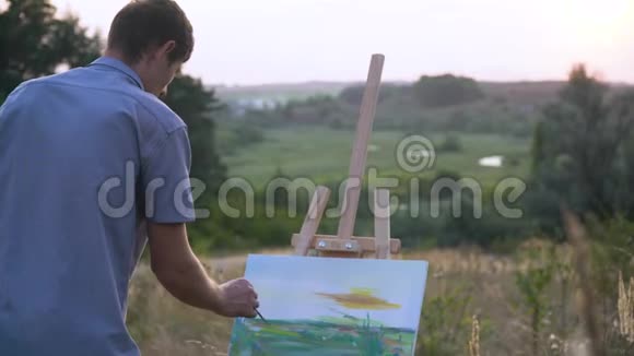 男性艺术家在户外自然景观中描绘日落景观一个人画了一幅画视频的预览图
