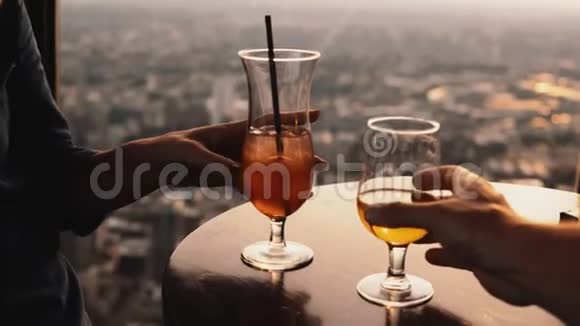 摩天大楼餐厅的桌子上立着两杯鸡尾酒的近景男人和女人在浪漫的约会视频的预览图