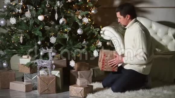 快乐的父亲把礼物盒藏在圣诞树下视频的预览图