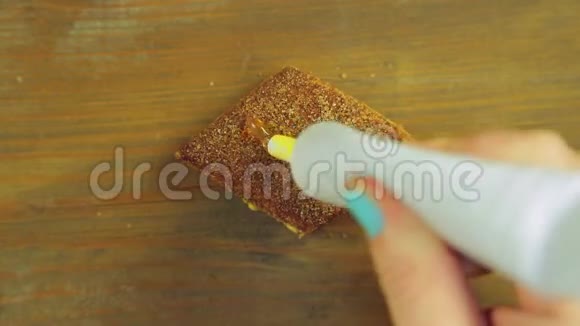 一只手拿着一管烹饪涂料在带有黄色油漆的巧克力饼干上画着滑稽的脸手工制作视频的预览图