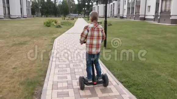 无法辨认的男孩正在家附近骑着陀螺滑板车后景视频的预览图
