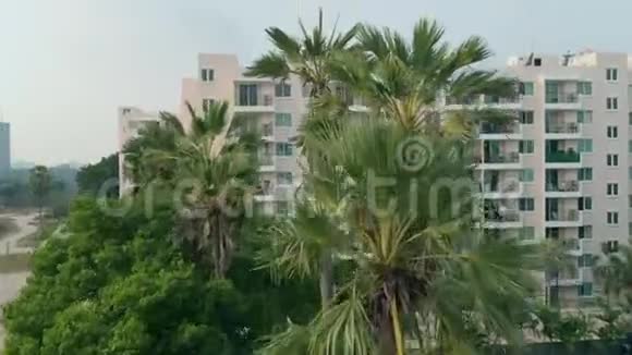 鸟瞰热带村庄城市上景拍摄游泳池环绕棕榈树和美丽的热带绿色花园视频的预览图