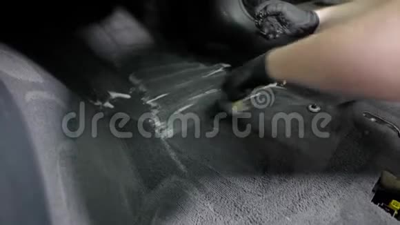 工人正在清理汽车里的地毯用刷子用刷子摩擦泡沫用黑色橡胶手套拿着它特写镜头视频的预览图