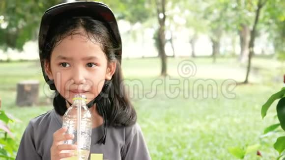 可爱的亚洲小女孩在自然公园快乐地喝水视频的预览图