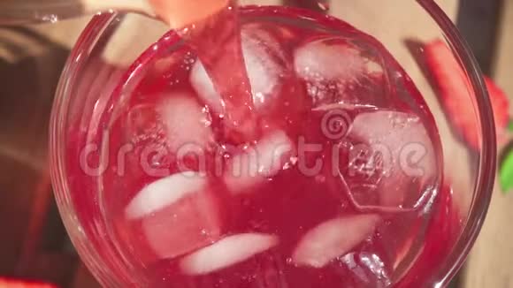 慢动作的果汁从水壶里倒入一个装有冰块的杯子里视频的预览图