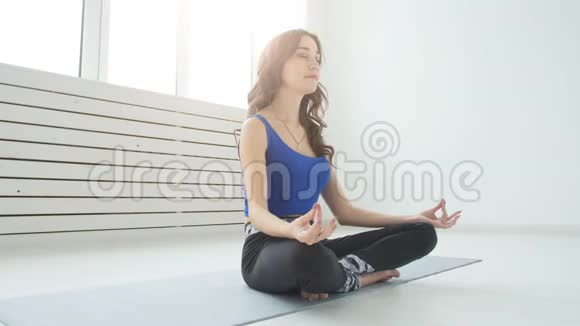 瑜伽和家庭健身的概念年轻女子在室内练习瑜伽时进行冥想视频的预览图