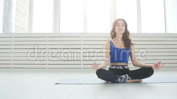 瑜伽和家庭健身的概念年轻女子在室内练习瑜伽时进行冥想视频的预览图