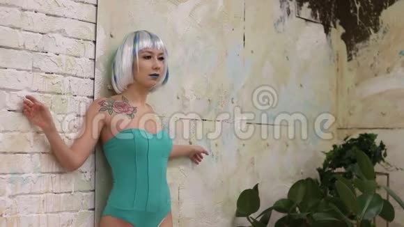 戴着假发和紧身衣的美女站在墙边视频的预览图