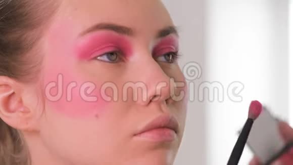 眼妆师应用和羽毛眼影粉漂亮的女人模特脸特写镜头视频的预览图