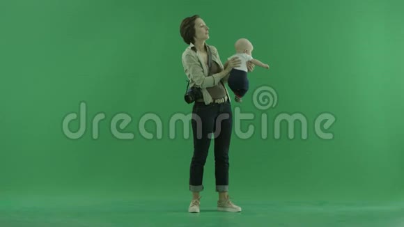 一个年轻的女人把她的孩子举在绿色的屏幕上视频的预览图