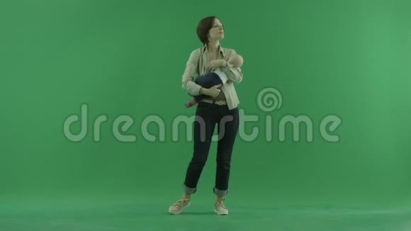 一个年轻的女人在绿色的屏幕上摇动她的孩子视频的预览图