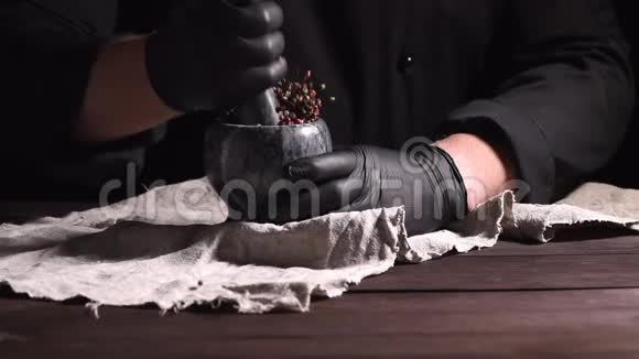 黑乳胶手套中的厨师拿着一个混合胡椒的石砂浆烹饪和研磨香料视频的预览图