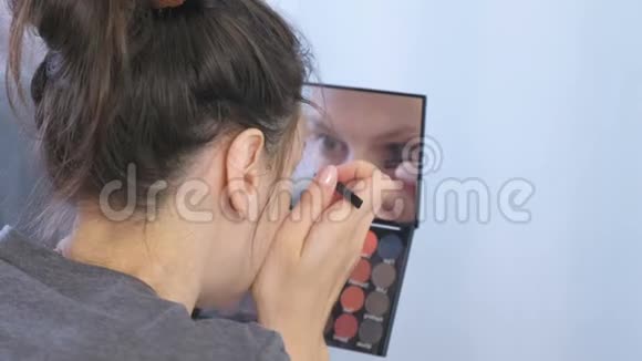 年轻的黑发女人在家里的镜子前用镊子夹住眉毛视频的预览图
