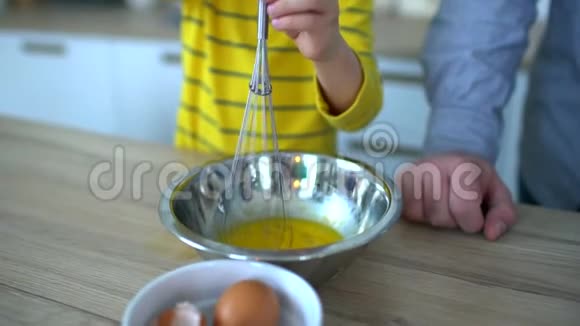 非常可爱的小男孩在厨房里搅拌鸡蛋做炒鸡蛋可爱的爸爸可爱的小男孩视频的预览图