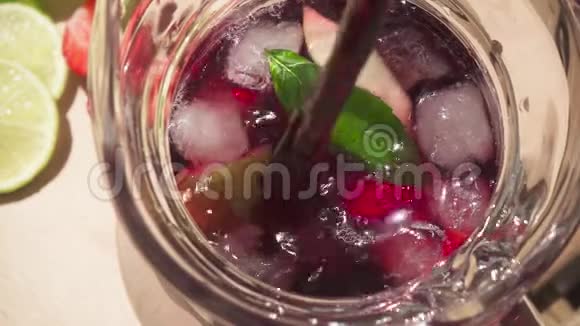 在装有冰块和水果的玻璃瓶中缓慢运动以倒入葡萄酒视频的预览图