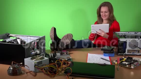 放松的女技师腿在桌子上玩平板电脑视频的预览图