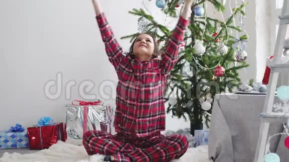 快乐的年轻漂亮女人在装饰好的工作室里的圣诞树附近扔纸屑慢动作3840x2160视频的预览图