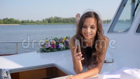 美丽的女孩在夏天休息时在帆船上打电话视频的预览图