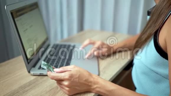 网上购物概念女人手拿信用卡用手提电脑视频的预览图