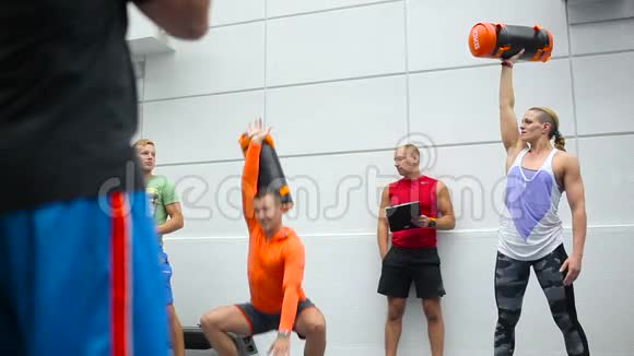 教练在健身房为年轻人展示体育锻炼视频的预览图