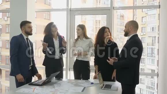 办公室工作人员一家大公司的雇员两名青年男子和三名青年妇女站在一张有文件的桌子旁视频的预览图