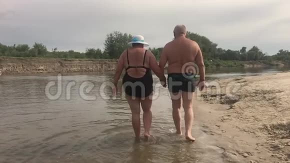 成熟的夫妻拥抱俯瞰河流一对漂亮的老人在水边快乐老人牵着手视频的预览图