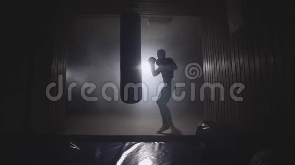 强壮的运动员在黑暗的健身房中缓慢运动的拳击袋青年培训视频的预览图