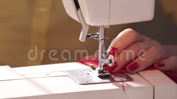 女人用现代缝纫机缝纫在机器上缝纫时支撑羊毛布的手红色布料女人视频的预览图