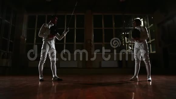 在体育馆里穿着击剑训练服装的年轻男女穿上西装开始战斗在里面视频的预览图