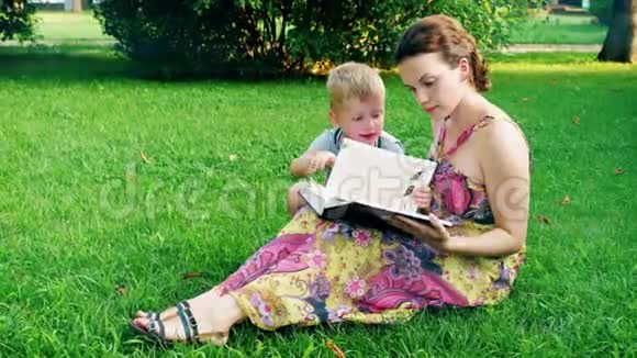 母子俩在草地上的公园里读一本书视频的预览图