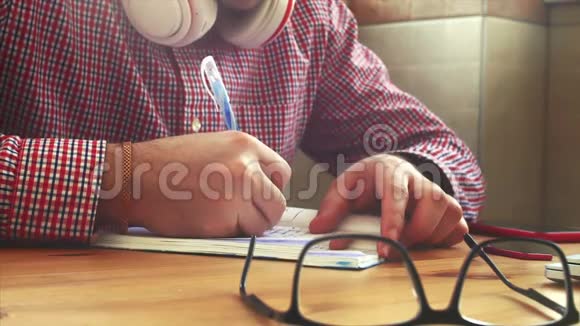 年轻的商人坐在桌边喝咖啡做工作写在一本书里忙碌的人写作业股票视频的预览图