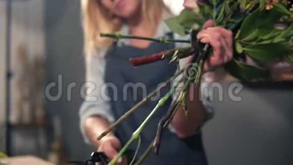专业女性花艺师准备花束花艺师在花店切花茎手工制作的花艺视频的预览图