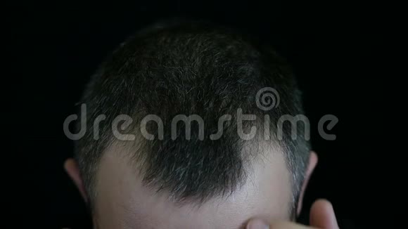 一个男人摸着他的头发在黑色的背景下人的头发是灰色的视频的预览图