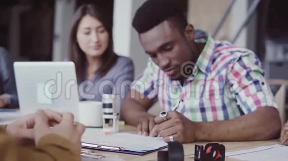 非洲和白种人的两个伙伴签署了一份合同一群人在办公室的背景上鼓掌慢节奏视频的预览图