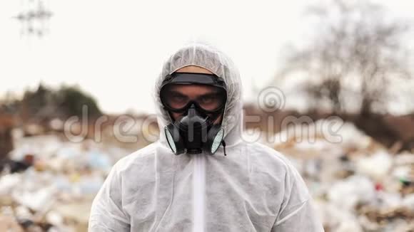 病毒学家穿着防护服装戴着防毒面具在垃圾填埋场的污染生态和生态中照相机观察视频的预览图