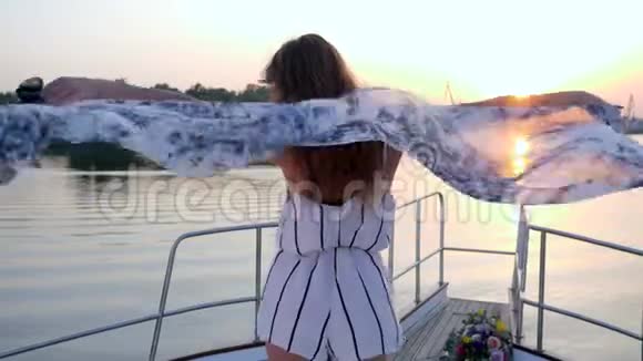在夕阳下快乐的女孩在游艇上迎风挥手视频的预览图