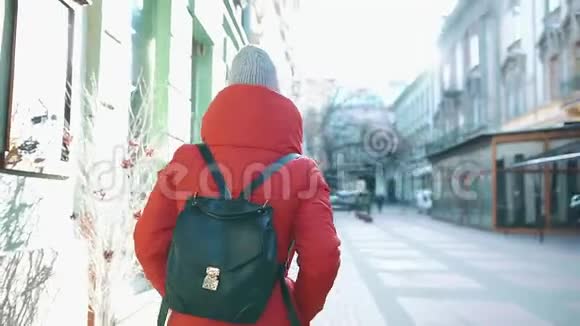 太阳照耀着站在街上的一个穿红色冬装的女孩视频的预览图