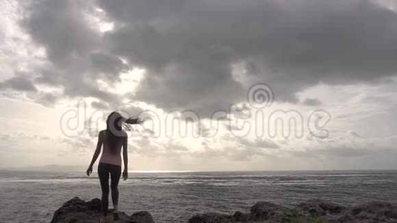跑步的女人举起双手站在海边的悬崖上视频的预览图