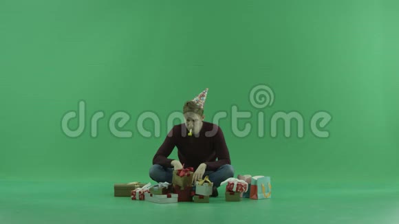 男人一边摇礼物一边坐在圣诞礼物中绿色的关键背景视频的预览图