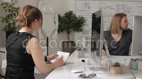 女专家与坐在公司电脑旁的同事交谈视频的预览图