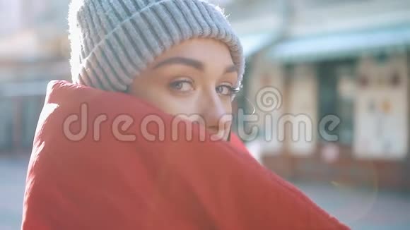 太阳照耀着站在街上的一个穿红色冬装的女孩视频的预览图