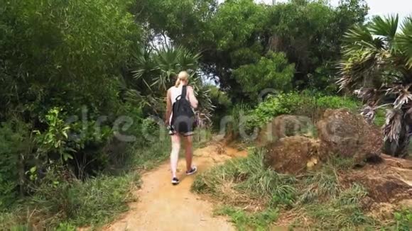 旅游女孩正沿着热带雨林的小径散步视频的预览图