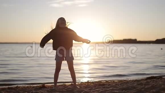 日落时分美丽的女孩在湖边跳舞视频的预览图
