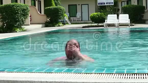中年男子在酒店游泳池放松和慢慢游泳视频的预览图