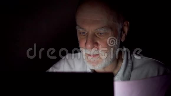 疲惫的资深商人在深夜用笔记本电脑工作只有一张漆黑的脸视频的预览图
