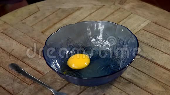 木桌上用蓝色碗叉搅拌鸡蛋视频的预览图