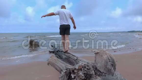 一个人试图在靠近大海的树上保持平衡视频的预览图