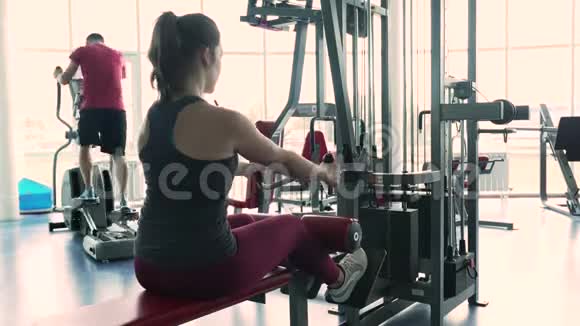 运动女性在模拟器机器上训练背部肌肉视频的预览图